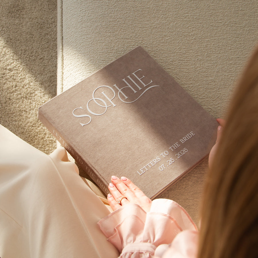 Personalized book titled 'Letters to the Bride' held by a person with a textured wall background