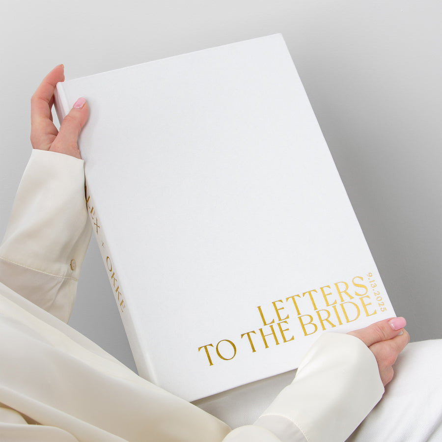 Hand holding a book titled 'Letters to the Bride' against a gray background